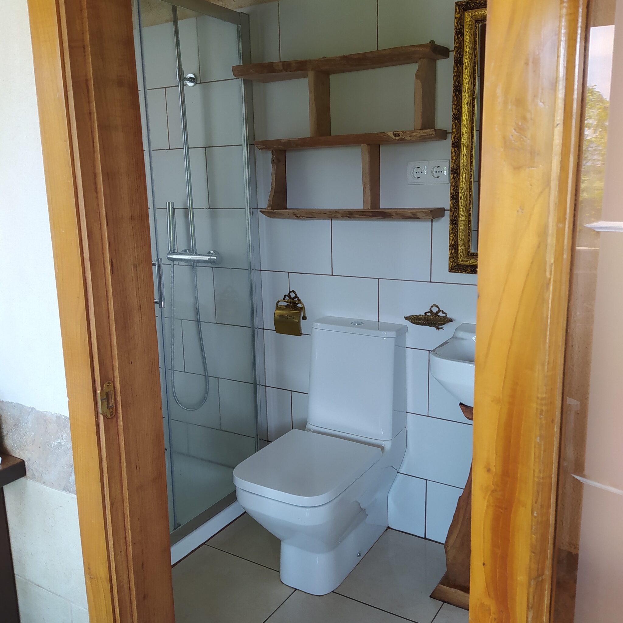 Baño privado en casa rural Loventuro con combinación de piedra, madera y funcionalidad.