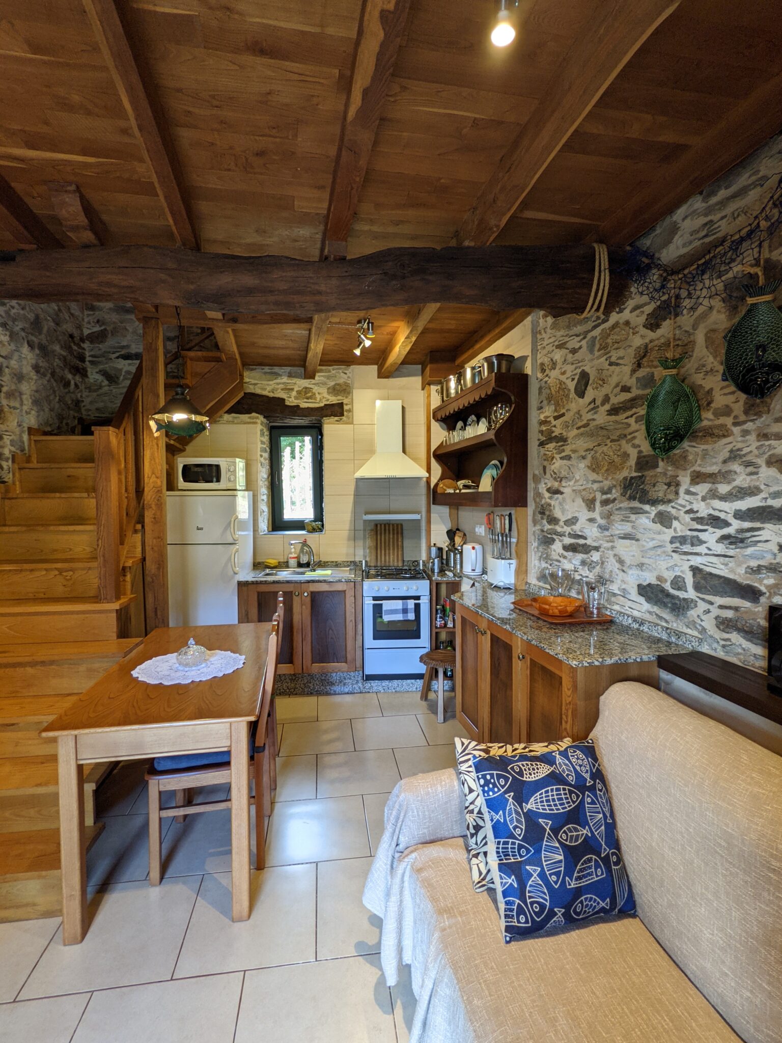 Cocina de estilo rústico en Loventuro con todos los servicios modernos para disfrutar de una estancia cómoda. Interior de la casa rural Loventuro con muros de piedra y techos de madera que conservan el encanto gallego.